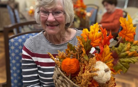 Woman holds basket of fall crafts